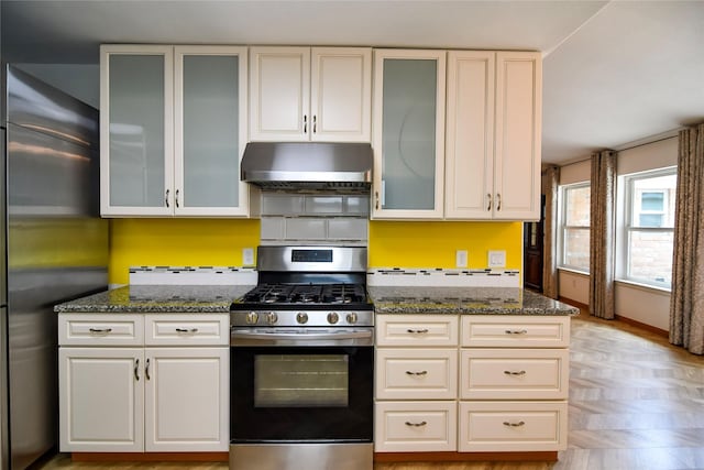 2106 Silver Falls Dr, Houston, TX 77339 - kitchen featuring stainless steel appliances, under cabinet range hood, dark stone countertops, and glass insert cabinets