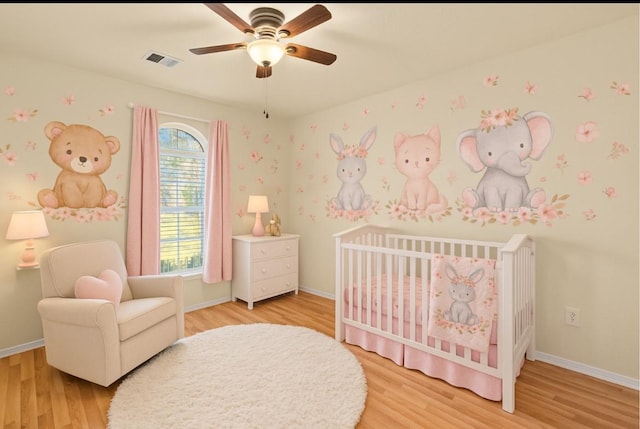 17031 Pelorus Way, Crosby, TX 77532 - bedroom featuring a crib, light wood-style floors, and ceiling fan