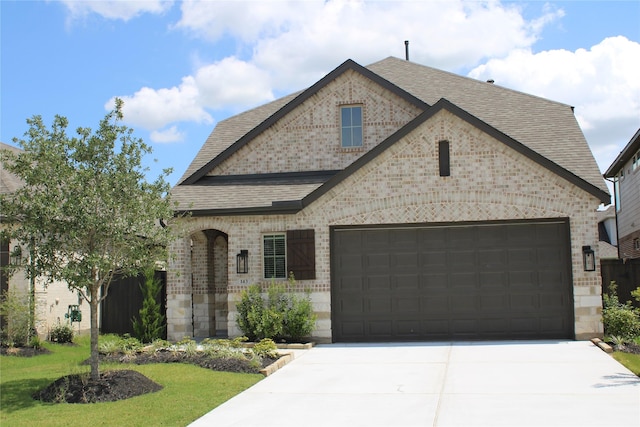 143 Nightshade St, Richmond, TX 77406 - french country inspired facade with brick siding, roof with shingles, driveway, and a garage