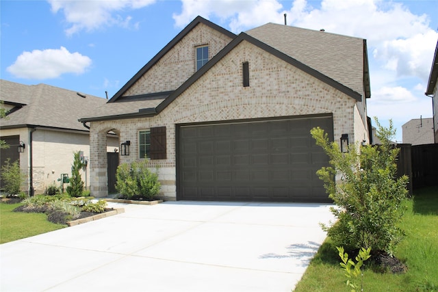 143 Nightshade St, Richmond, TX 77406 - french country inspired facade featuring brick siding, a garage, driveway, and a shingled roof