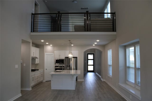 143 Nightshade St, Richmond, TX 77406 - kitchen featuring appliances with stainless steel finishes, a towering ceiling, arched walkways, a sink, and white cabinetry