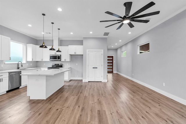 5029 Creekmont Dr, Houston, TX 77091 - kitchen featuring appliances with stainless steel finishes, ornamental molding, a kitchen island, ceiling fan, and white cabinets