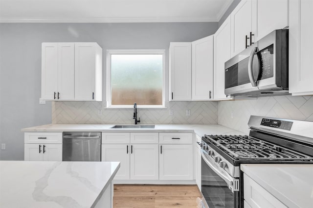 5029 Creekmont Dr, Houston, TX 77091 - kitchen featuring appliances with stainless steel finishes, a sink, crown molding, light stone countertops, and white cabinetry