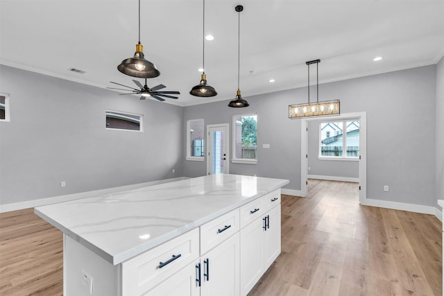 5029 Creekmont Dr, Houston, TX 77091 - kitchen featuring light wood-style floors, decorative light fixtures, white cabinets, a kitchen island, and light stone countertops