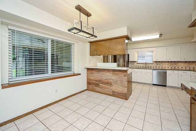 19515 Oak Timbers Dr, Humble, TX 77346 - kitchen with stainless steel dishwasher, a peninsula, a sink, white cabinetry, and tasteful backsplash