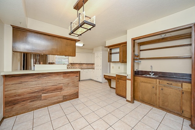 19515 Oak Timbers Dr, Humble, TX 77346 - kitchen featuring a sink, light tile patterned floors, brown cabinetry, a peninsula, and white cabinetry