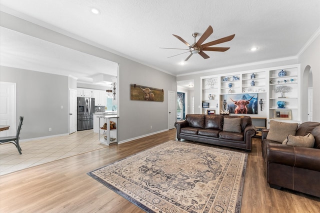 3102 E Elm Cir, Katy, TX 77493 - living area with ceiling fan, crown molding, arched walkways, light wood-style floors, and baseboards