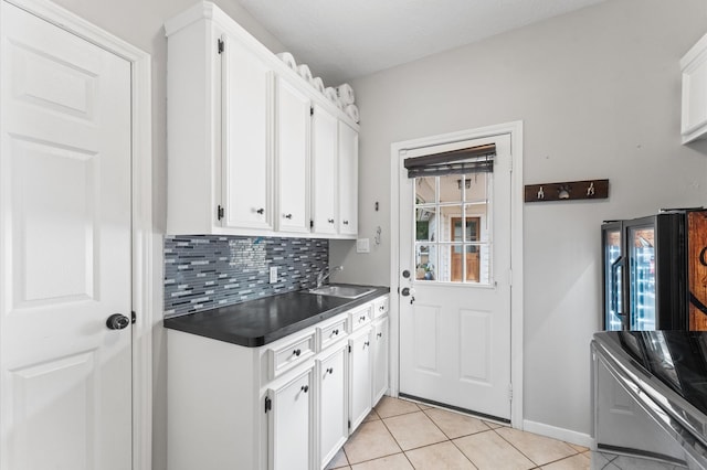 3102 E Elm Cir, Katy, TX 77493 - kitchen with dark countertops, a sink, light tile patterned floors, white cabinets, and backsplash