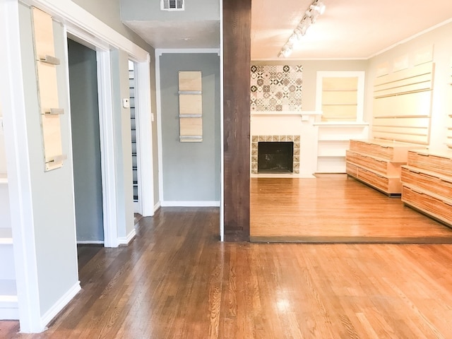 1632 W Alabama St, Houston, TX 77006 - unfurnished living room featuring wood finished floors, rail lighting, a tile fireplace, baseboards, and crown molding