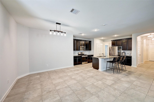 31702 Casa Linda Dr, Hockley, TX 77447 - kitchen featuring appliances with stainless steel finishes, backsplash, arched walkways, a kitchen bar, and recessed lighting