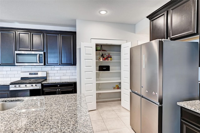 31702 Casa Linda Dr, Hockley, TX 77447 - kitchen with stainless steel appliances, light stone countertops, tasteful backsplash, light tile patterned floors, and recessed lighting