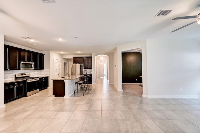 31702 Casa Linda Dr, Hockley, TX 77447 - kitchen with stainless steel appliances, ceiling fan, backsplash, a kitchen breakfast bar, and a kitchen island with sink
