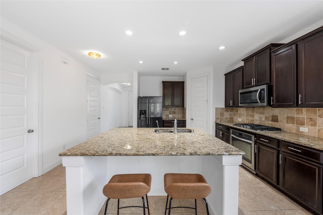 2206 Hidden Meadow Ln, Pearland, TX 77089 - kitchen featuring stainless steel appliances, a sink, tasteful backsplash, dark brown cabinets, and light stone countertops