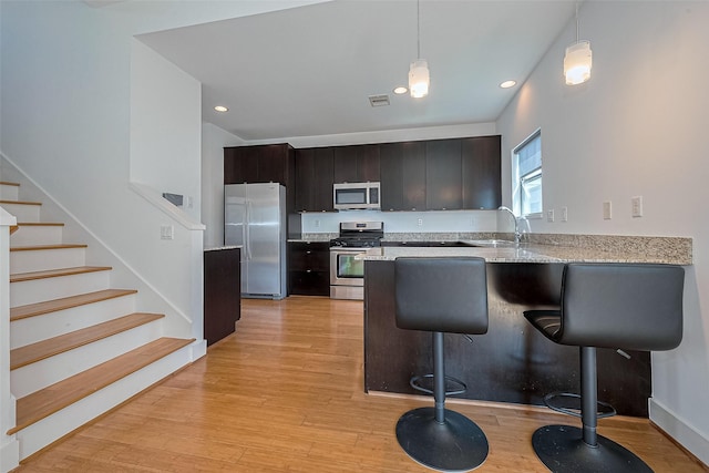 5012 Cornish St, Houston, TX 77007 - kitchen featuring stainless steel appliances, a peninsula, light wood-style flooring, pendant lighting, and a kitchen breakfast bar