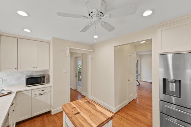 2044 Branard St, Houston, TX 77098 - kitchen featuring appliances with stainless steel finishes, light wood-type flooring, decorative backsplash, recessed lighting, and ceiling fan