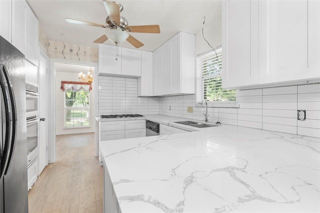 8903 Roos Rd, Houston, TX 77036 - kitchen featuring a sink, stainless steel appliances, white cabinetry, ceiling fan, and light stone countertops