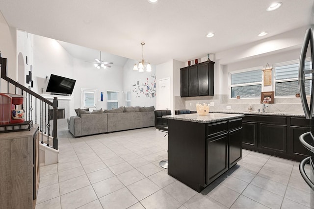 2507 Ocean Pass Ln, Richmond, TX 77469 - kitchen with dark cabinets, a chandelier, light tile patterned flooring, backsplash, and ceiling fan
