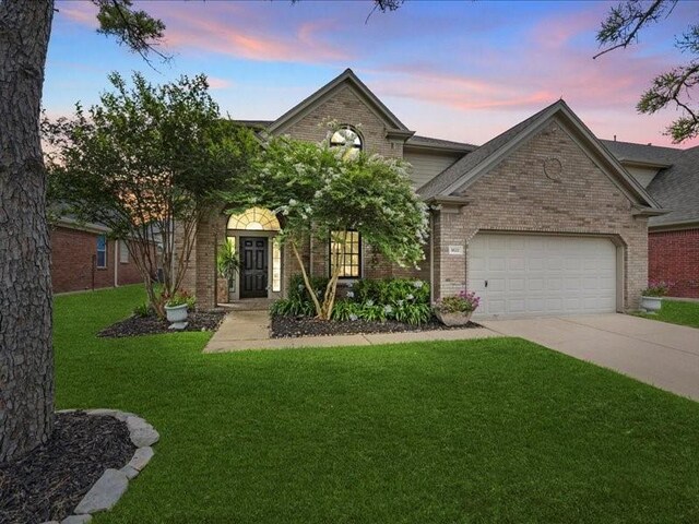 9622 Hanging Moss Trl, Houston, TX 77064 - view of front of home with brick siding, an attached garage, driveway, and a lawn