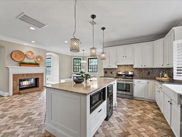9622 Hanging Moss Trl, Houston, TX 77064 - kitchen with stainless steel range with gas stovetop, brick floors, black microwave, crown molding, and a center island
