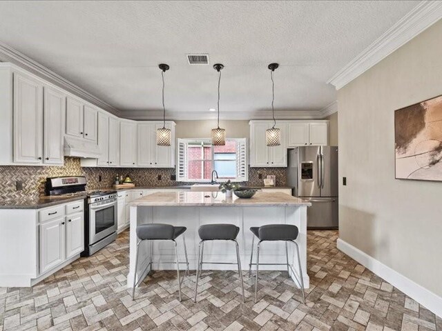 9622 Hanging Moss Trl, Houston, TX 77064 - kitchen featuring appliances with stainless steel finishes, under cabinet range hood, a breakfast bar area, tasteful backsplash, and white cabinets