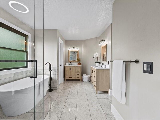 9622 Hanging Moss Trl, Houston, TX 77064 - bathroom with two vanities, a soaking tub, marble finish floors, and a textured ceiling