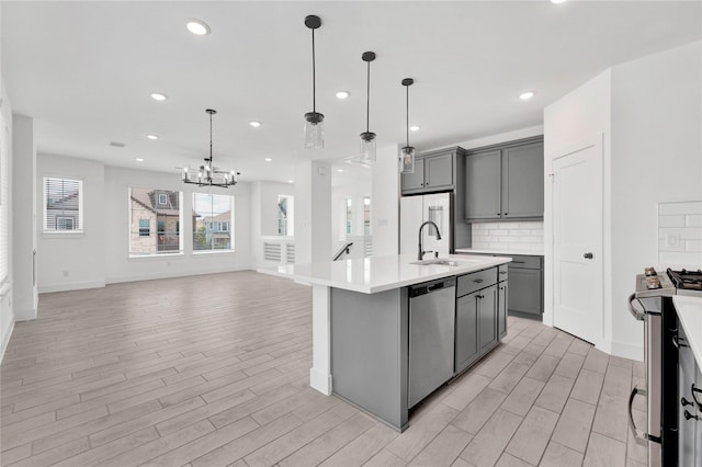 15147 Colorado Bend Park Dr, Cypress, TX 77433 - kitchen featuring gray cabinetry, appliances with stainless steel finishes, light countertops, light wood finished floors, and a chandelier
