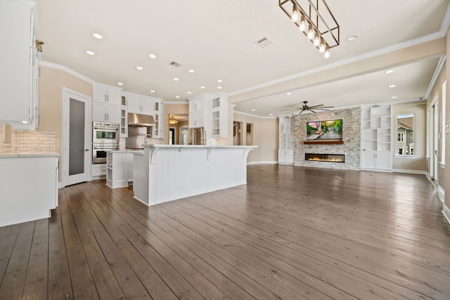 806 Quintana Roo Pl, Seabrook, TX 77586 - kitchen featuring a stone fireplace, a kitchen bar, open floor plan, white cabinetry, and light countertops