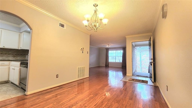 7900 Westheimer Rd Unit 228, Houston, TX 77063 - unfurnished dining area featuring ornamental molding, a chandelier, a textured ceiling, light wood-style floors, and arched walkways