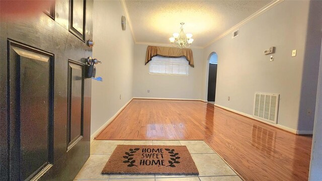 7900 Westheimer Rd Unit 228, Houston, TX 77063 - foyer with ornamental molding, a chandelier, wood finished floors, a textured ceiling, and arched walkways