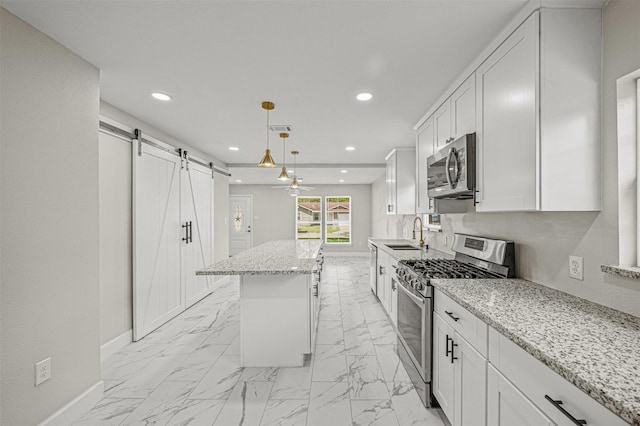 702 Norell St, Channelview, TX 77530 - kitchen featuring stainless steel appliances, a barn door, baseboards, a center island, and a sink