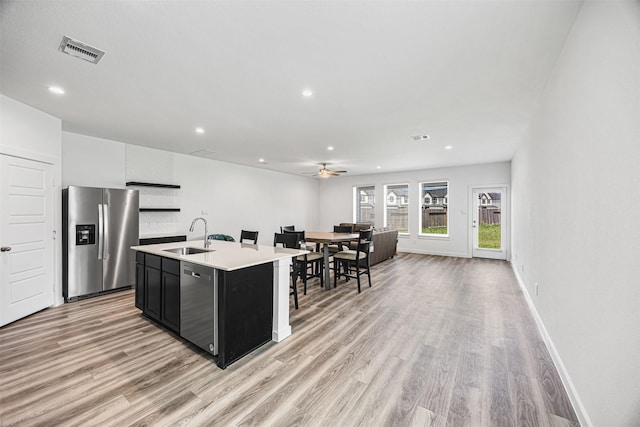 12305 Brandenburg Gate Dr, Houston, TX 77047 - kitchen with stainless steel appliances, a sink, dark cabinetry, light countertops, and light wood-style flooring