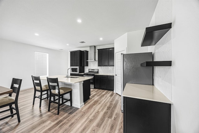12305 Brandenburg Gate Dr, Houston, TX 77047 - kitchen featuring stainless steel gas range oven, wall chimney range hood, dark cabinetry, a sink, and tasteful backsplash