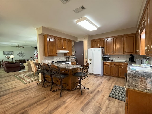 11683 Lakeshore Dr, Thornton, TX 76687 - kitchen with white refrigerator with ice dispenser, a sink, stove, a peninsula, and under cabinet range hood