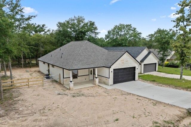 24696 Wicklow Rd, Hempstead, TX 77445 - view of front of home with roof with shingles, stone siding, an attached garage, driveway, and view of wooded area