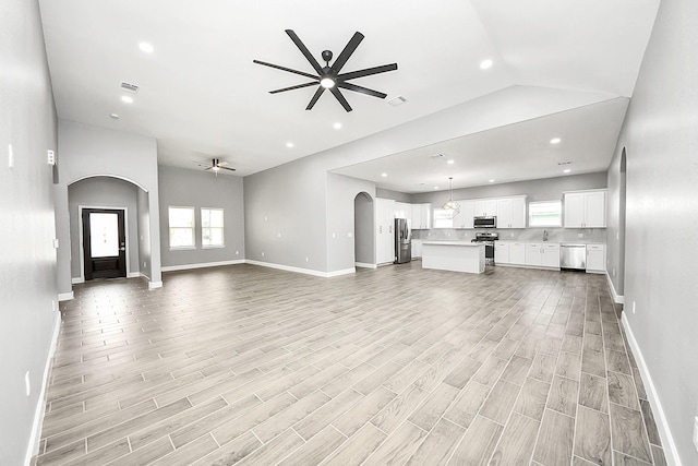 2448 Areba St, Houston, TX 77091 - unfurnished living room with a ceiling fan, arched walkways, baseboards, light wood-style floors, and recessed lighting