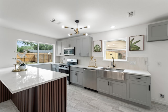 11819 Ryewater Dr, Houston, TX 77089 - kitchen featuring stainless steel appliances, gray cabinets, a sink, a chandelier, and decorative backsplash