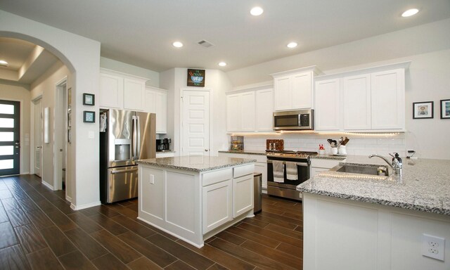 24618 Songlark Bend Dr, Tomball, TX 77375 - kitchen with appliances with stainless steel finishes, a sink, arched walkways, backsplash, and white cabinets