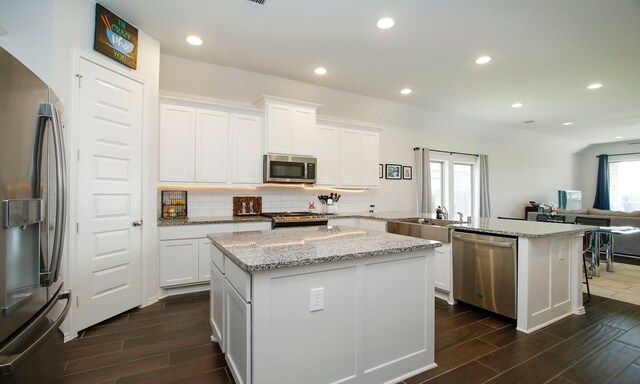 24618 Songlark Bend Dr, Tomball, TX 77375 - kitchen with appliances with stainless steel finishes, a peninsula, wood finish floors, backsplash, and recessed lighting