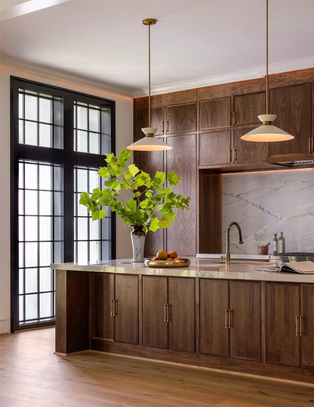 2218 Bartlett St, Houston, TX 77098 - kitchen featuring light wood-style floors, ornamental molding, pendant lighting, light countertops, and tasteful backsplash