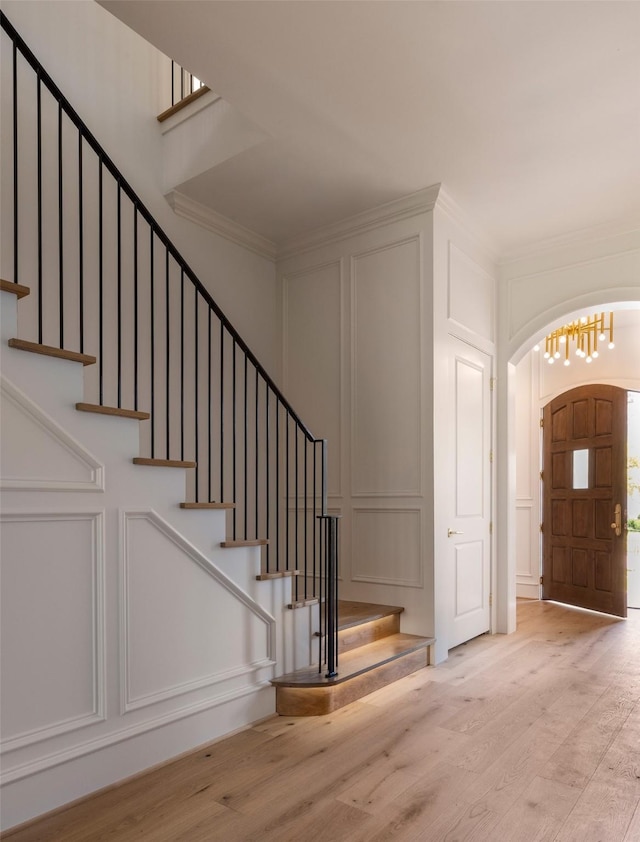 2218 Bartlett St, Houston, TX 77098 - foyer entrance featuring a decorative wall, wood finished floors, arched walkways, stairs, and crown molding
