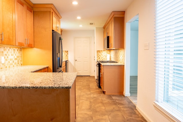 217 Wellwood Ln, Conroe, TX 77304 - kitchen with white microwave, gas range, recessed lighting, backsplash, and refrigerator with ice dispenser