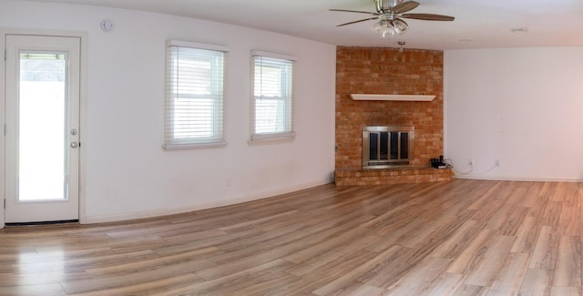 217 Wellwood Ln, Conroe, TX 77304 - unfurnished living room featuring light wood finished floors, a ceiling fan, a fireplace, and baseboards