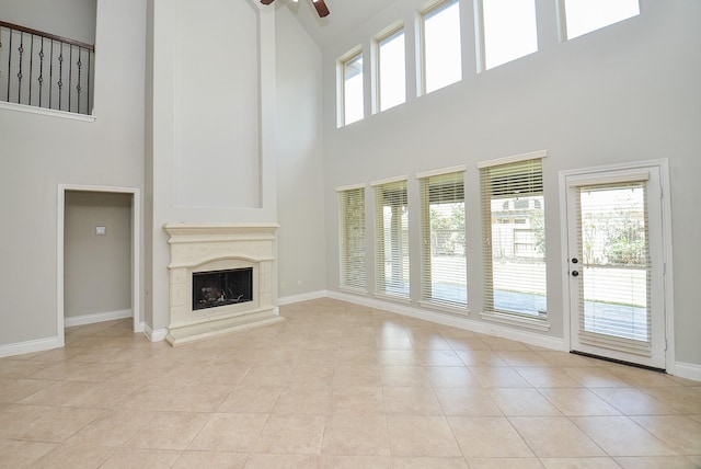 9819 St Romain Dr, Katy, TX 77494 - unfurnished living room featuring a towering ceiling, ceiling fan, plenty of natural light, baseboards, and a fireplace with raised hearth