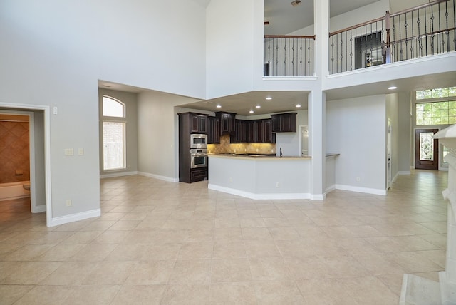 9819 St Romain Dr, Katy, TX 77494 - unfurnished living room with light tile patterned floors, a towering ceiling, baseboards, and a sink