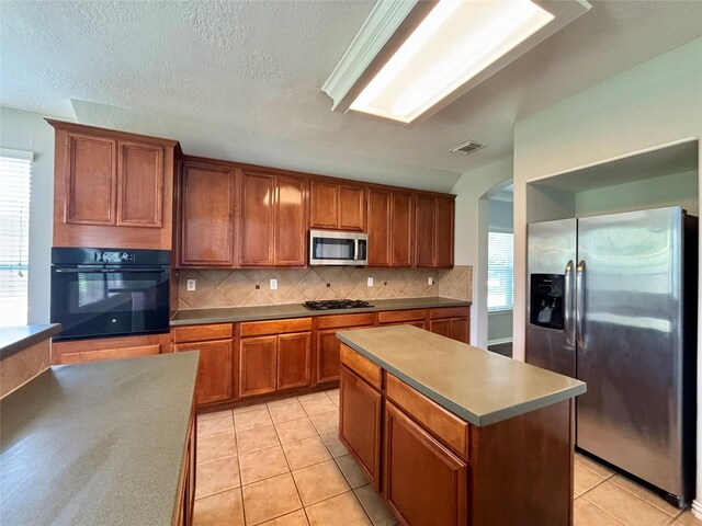 2528 Attwater Way, League City, TX 77573 - kitchen with black appliances, brown cabinets, light tile patterned floors, backsplash, and arched walkways