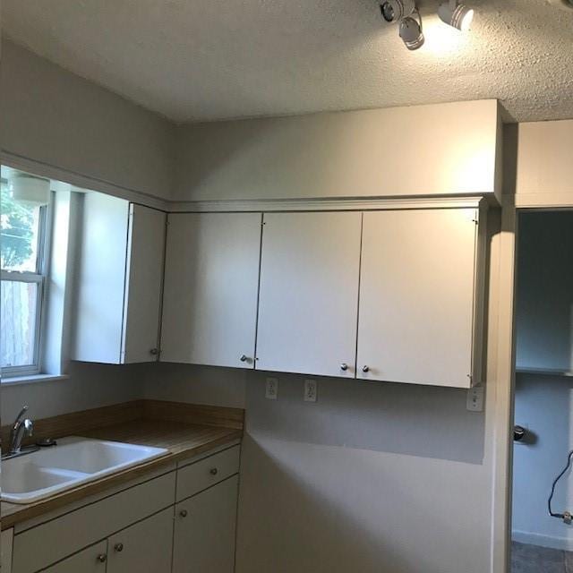 5471 Kuldell Dr, Houston, TX 77096 - kitchen featuring a sink, white cabinetry, and a textured ceiling