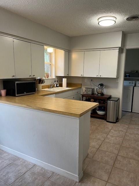 5471 Kuldell Dr, Houston, TX 77096 - kitchen with stainless steel microwave, a sink, washing machine and clothes dryer, a textured ceiling, and light countertops