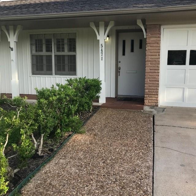 5471 Kuldell Dr, Houston, TX 77096 - doorway to property with a shingled roof, board and batten siding, a garage, driveway, and covered porch
