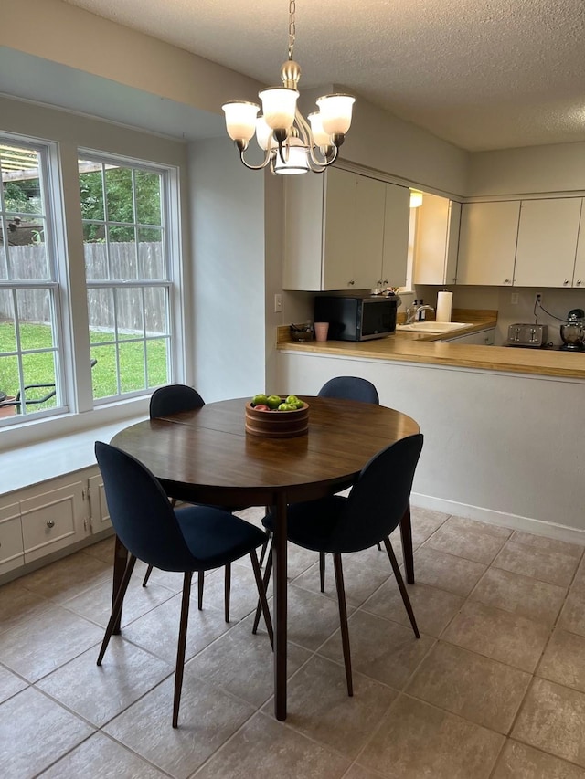 5471 Kuldell Dr, Houston, TX 77096 - dining space with a chandelier, plenty of natural light, a textured ceiling, and light tile patterned floors