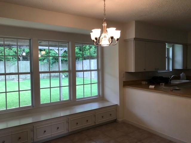 5471 Kuldell Dr, Houston, TX 77096 - tiled dining area with plenty of natural light, a sink, a chandelier, baseboards, and a textured ceiling